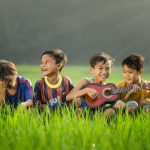 Kids' Shelves - four boys laughing and sitting on grass during daytime