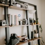 Shelving Units - a shelf filled with cameras and books on top of a wall