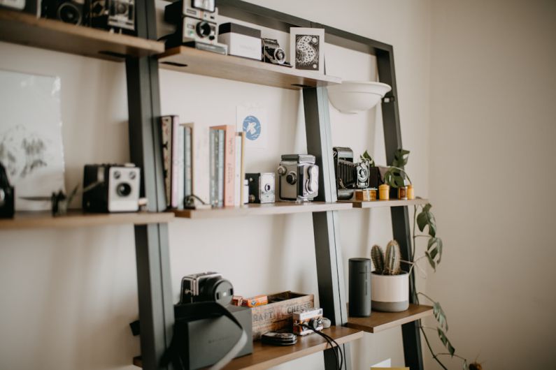 Shelving Units - a shelf filled with cameras and books on top of a wall