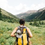 Outdoor Shelves - person carrying yellow and black backpack walking between green plants